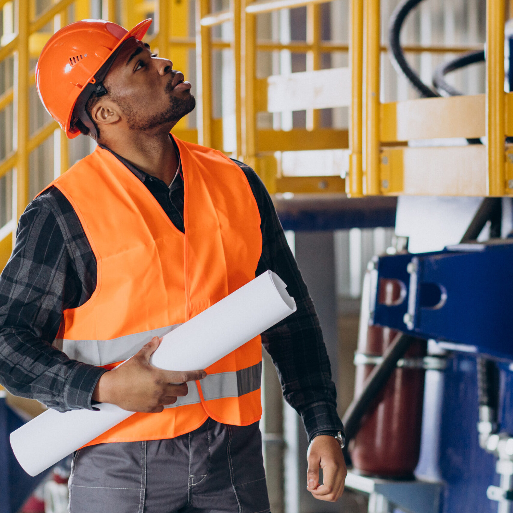 African american worker standing in uniform wearing a safety hat in a factory